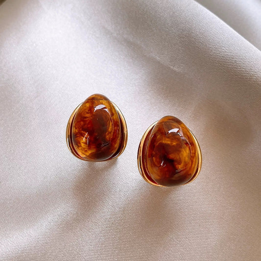 Amber teardrop stud earrings with polished gold-tone edge
