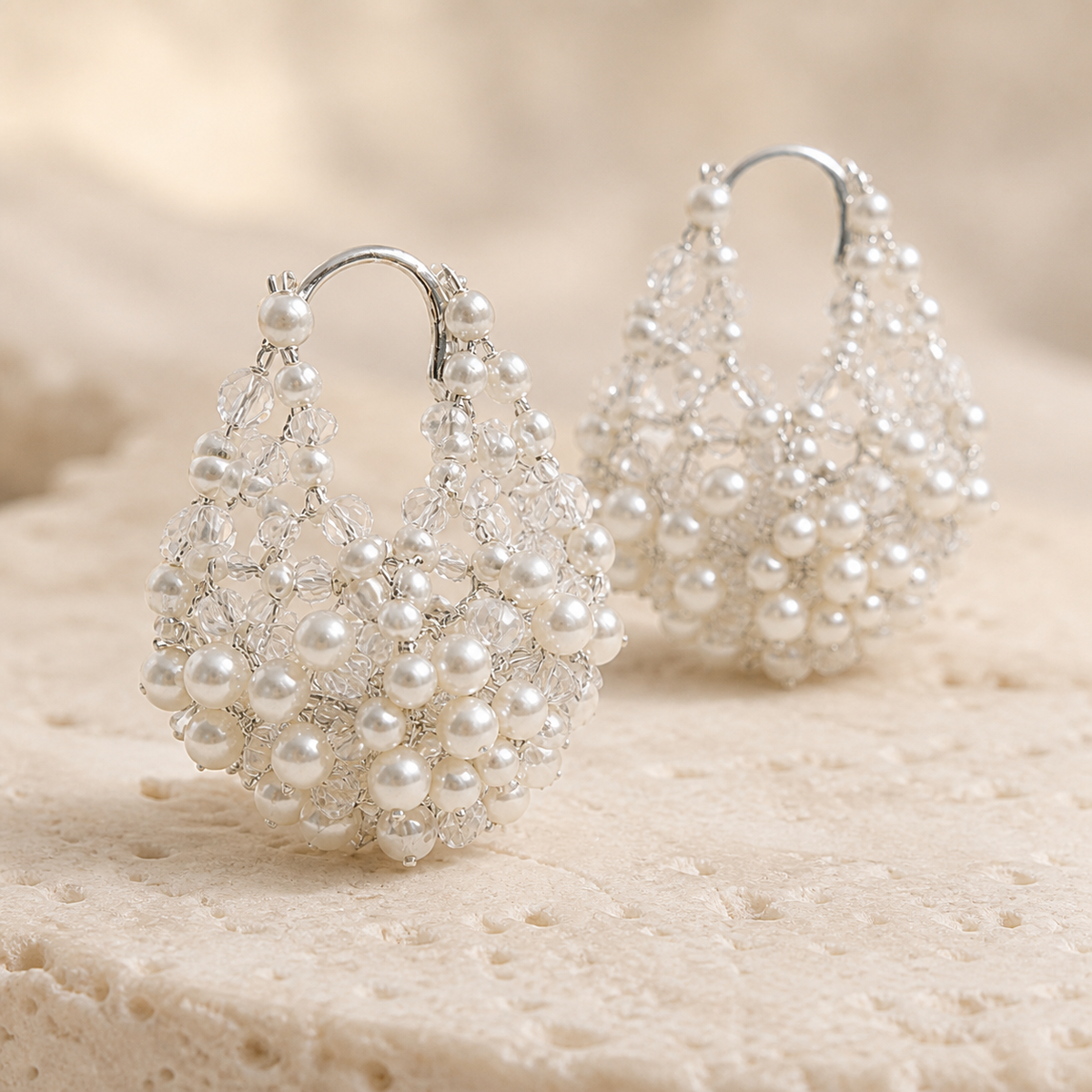 Macro detail of silver sculptural pearl and crystal teardrop hoop earrings