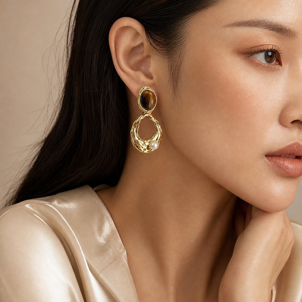 Woman wearing a tiger eye and pearl gold drop earring